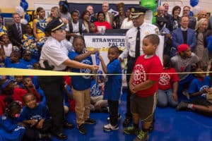 Police officers and kids cut the ribbon at the PAL Center
