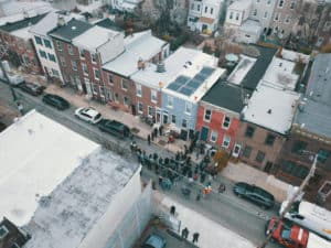 Aerial view of a solar panel installation on top of a building with expanded view of the neighborhood