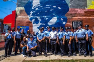 Community members and police officers standing in front the the mural honoring Sergeant Robert Wilson