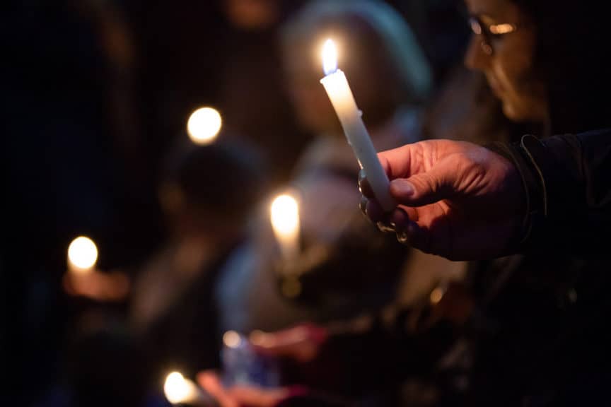 Close up of hands holding lighted candles at a vigil