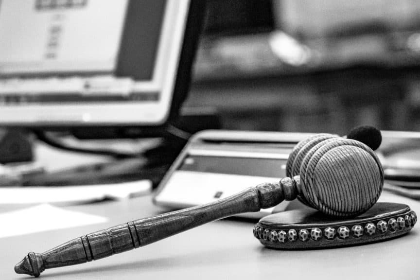 A judge's gavel resting on a desk next to a computer