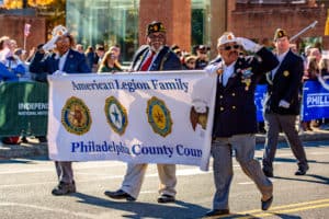 American Legion marching in the Veterans' day parade holding a banner
