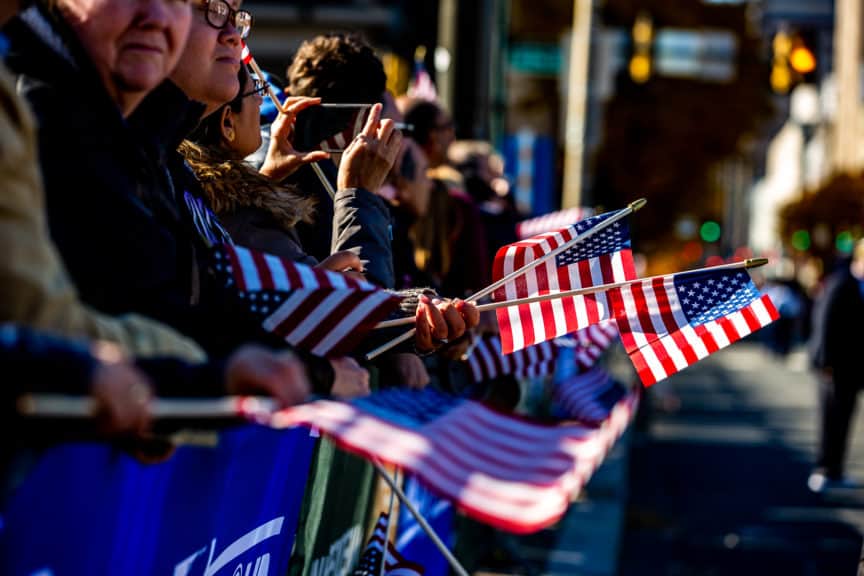 Onlookers wave US flags at the Veterans' Day Parade