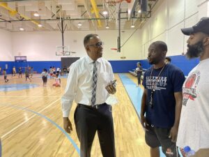 Councilmembers Clarke, Thomas and a third man on a indoor basketball court at a youth camp event