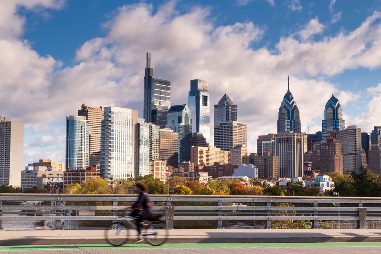 Skyline with cyclist on South Street Bridge riding towards University City , Philadelphia, Pennsylvania, USA