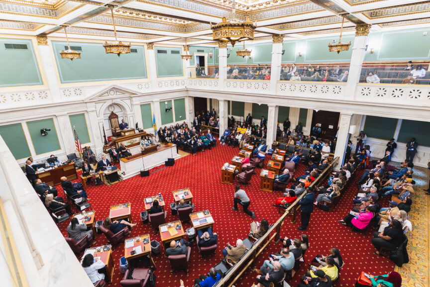 A wide-angle view of the ornate Philadelphia City Council chamber during Mayor Cherelle L. Parker's Fiscal Year 2027 Budget Address. The Mayor stands at the center podium, facing a full assembly of council members seated at the historic wooden dais, with spectators and staff filled throughout the room under high arched ceilings.